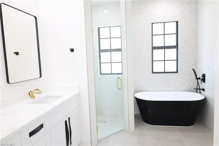 Bathroom featuring a stall shower, double vanity, and light tile patterned floors