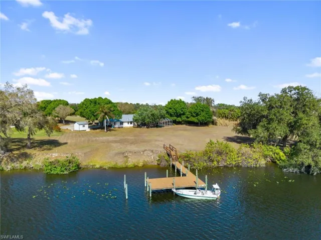 Dock area with a water view and view of scattered trees