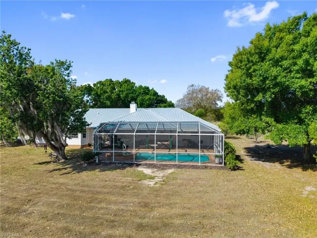 Swimming pool featuring a yard, a lanai, and a sunroom