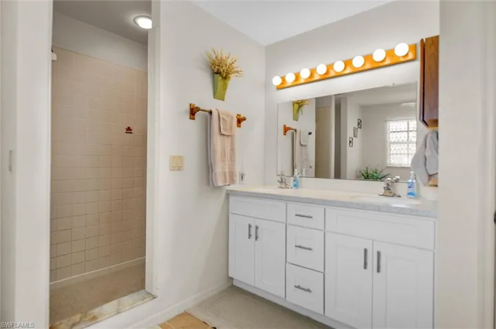 Full bath featuring double vanity, a stall shower, and light tile patterned floors