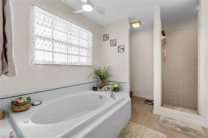 Full bath featuring a shower stall, light tile patterned floors, a garden tub, and a ceiling fan
