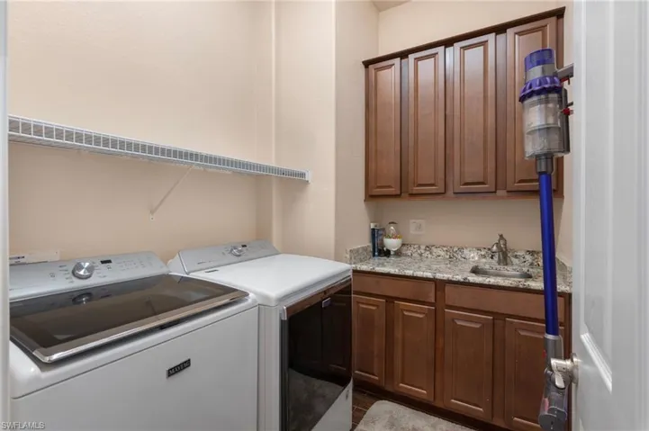 Washroom with sink, cabinets, and washer and dryer