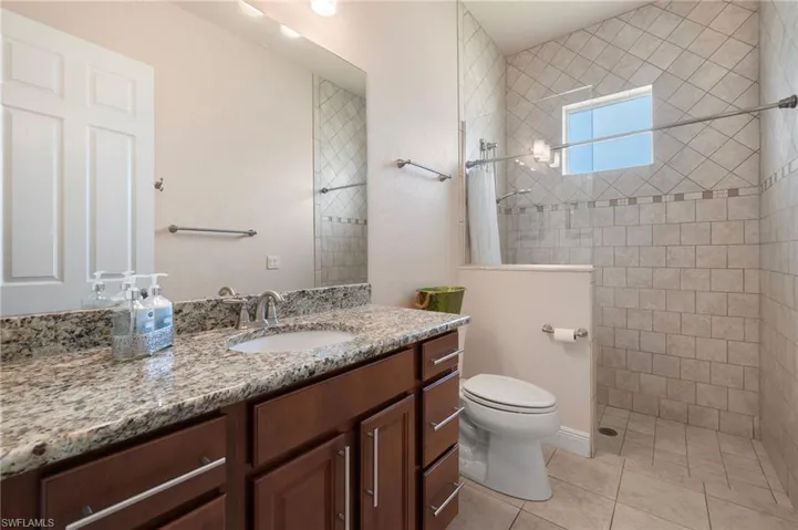 Bathroom featuring tile patterned floors, a shower with curtain, toilet, and vanity