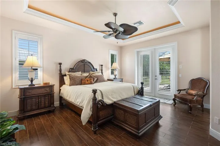 Bedroom featuring french doors, access to outside, dark hardwood / wood-style floors, ceiling fan, and a raised ceiling