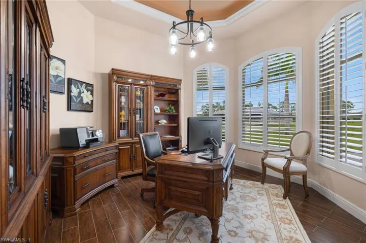 Office space with a notable chandelier, dark hardwood / wood-style flooring, and a raised ceiling