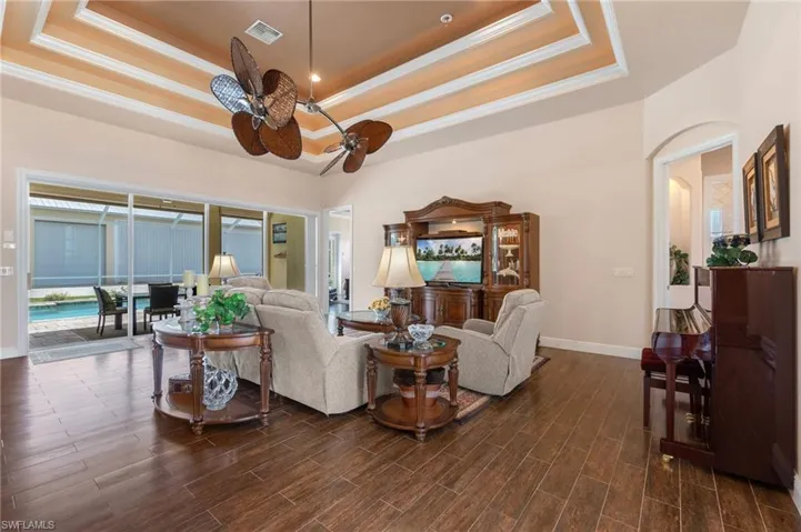 Living room featuring ceiling fan, a tray ceiling, and hardwood / wood-style floors
