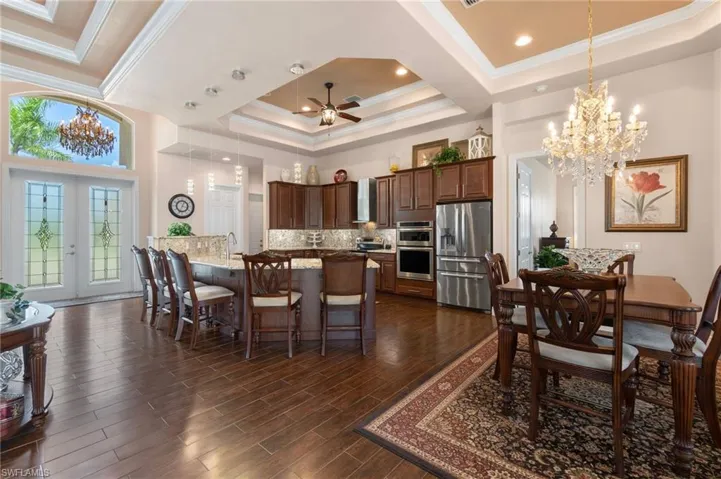 Dining area with crown molding, french doors, ceiling fan with notable chandelier, dark hardwood / wood-style flooring, and a raised ceiling