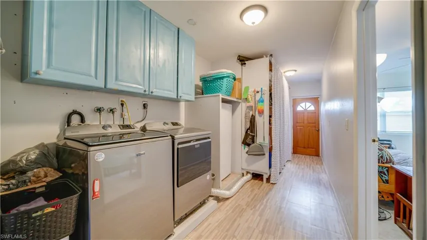 Kitchen with blue cabinets, light hardwood / wood-style flooring, and independent washer and dryer