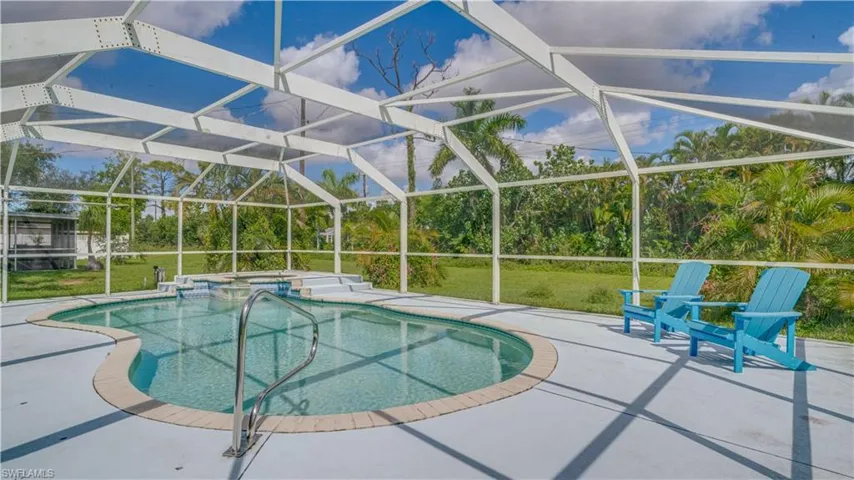 View of pool featuring a lawn, a lanai, an in ground hot tub, and a patio area