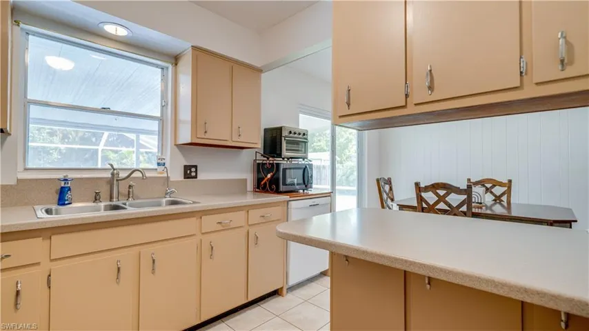 Kitchen with dishwasher, light tile patterned floors, and sink