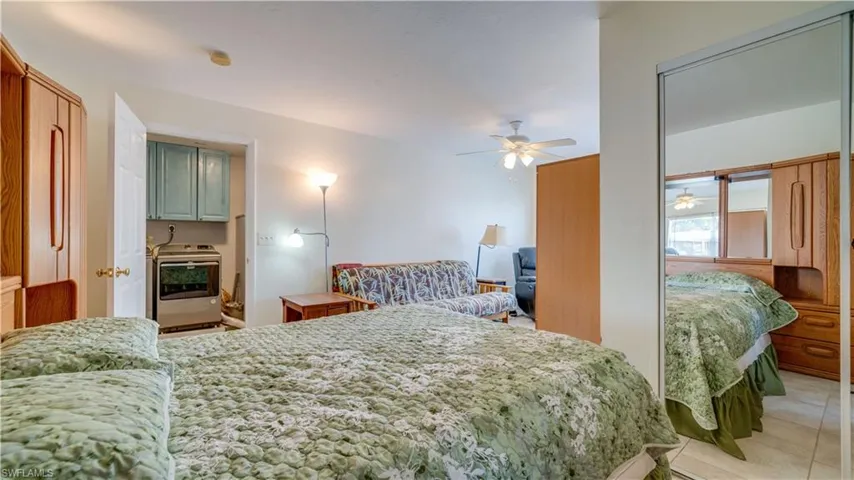 Bedroom featuring washer / dryer, ceiling fan, and light tile patterned floors