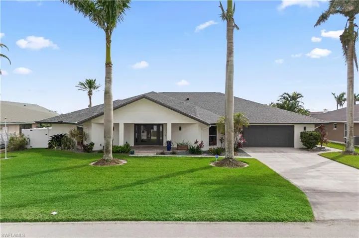 View of front of home featuring a garage, concrete driveway, a front lawn, and stucco siding