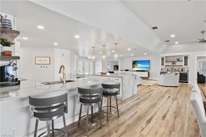 Kitchen with light stone counters, visible vents, a sink, and white cabinetry