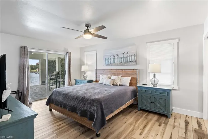 Bedroom featuring access to outside, baseboards, light wood-style flooring, and a ceiling fan