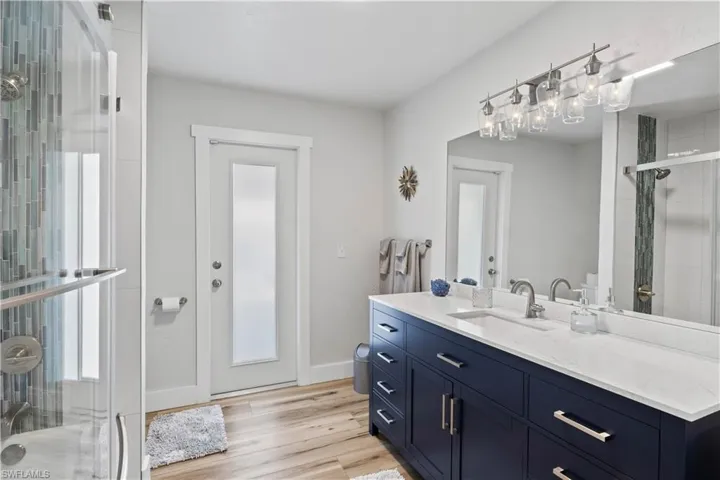 Full bath with a shower stall, baseboards, wood finished floors, and vanity