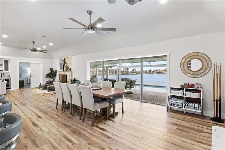 Dining room with light wood finished floors, visible vents, lofted ceiling, ceiling fan, and a water view
