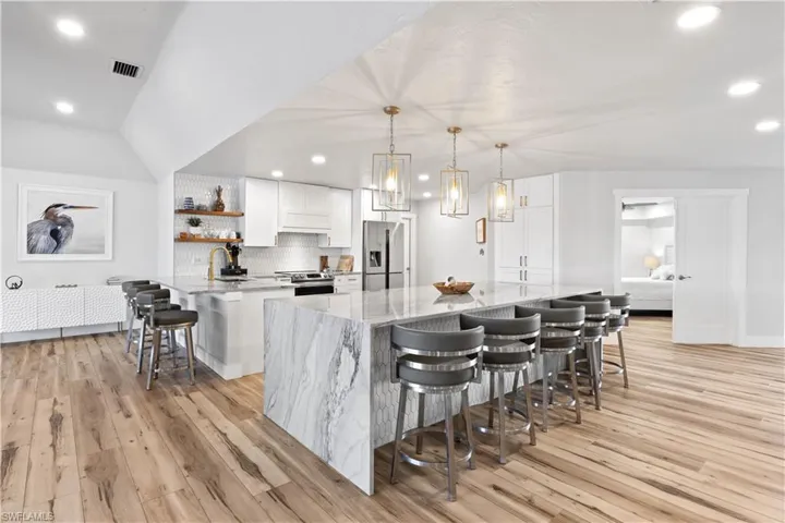 Kitchen with stainless steel appliances, a breakfast bar, white cabinets, and open shelves
