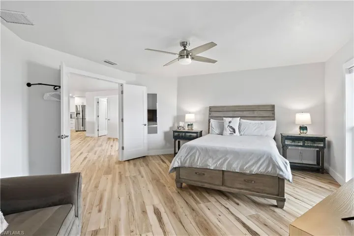 Bedroom featuring light wood-style floors, stainless steel fridge, visible vents, and baseboards