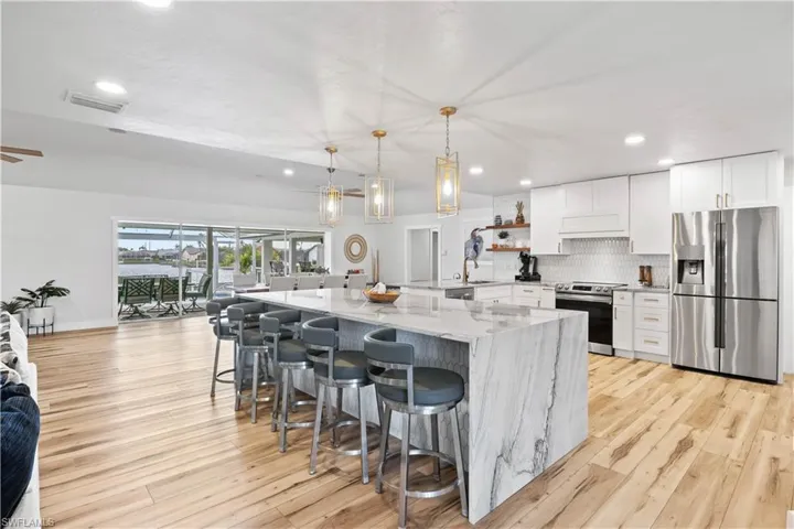 Kitchen featuring visible vents, white cabinets, light stone countertops, stainless steel appliances, and backsplash