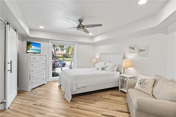 Bedroom featuring light wood-style floors, access to exterior, recessed lighting, and a barn door