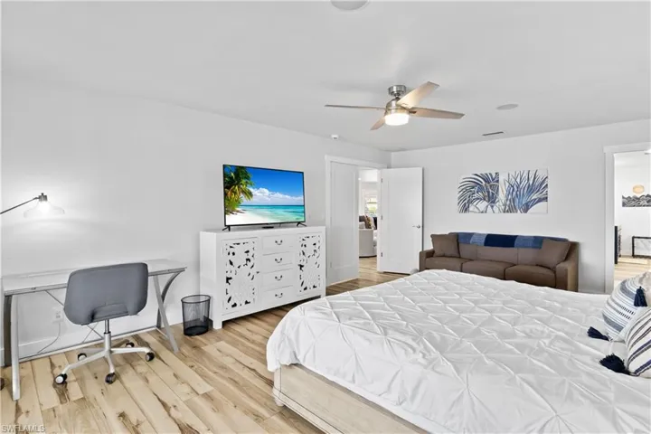 Bedroom with baseboards, wood finished floors, visible vents, and a ceiling fan