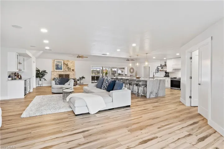 Living room featuring a ceiling fan, light wood-type flooring, a large fireplace, and recessed lighting