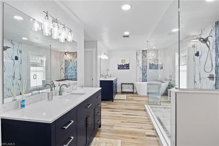 Full bath featuring visible vents, plenty of natural light, a marble finish shower, and wood finished floors