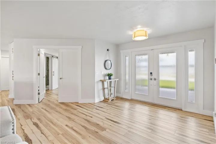 Foyer with french doors, wood finished floors, and baseboards