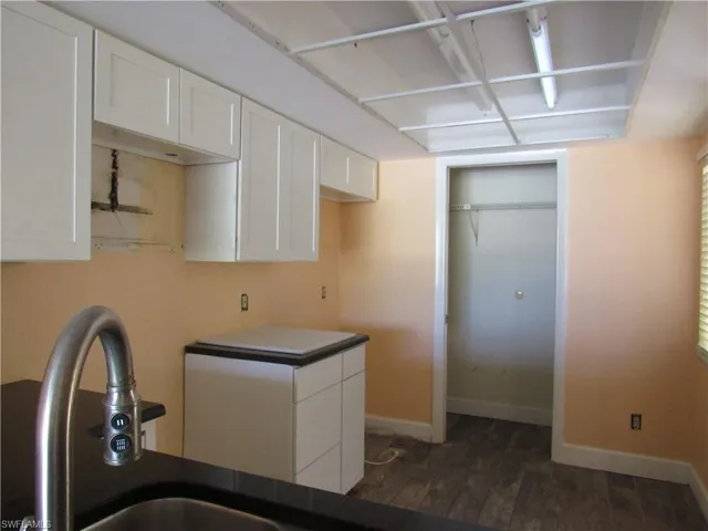 Kitchen with sink, white cabinetry, and dark wood-type flooring
