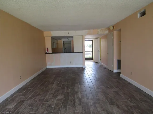 Unfurnished living room featuring sink, a textured ceiling, and dark wood-type flooring