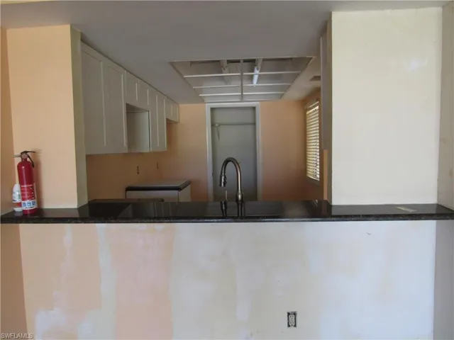 Kitchen featuring dark stone counters, sink, and white cabinets