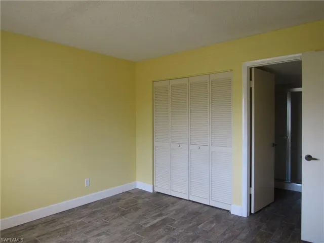 Unfurnished bedroom featuring dark hardwood / wood-style flooring, a closet, and a textured ceiling