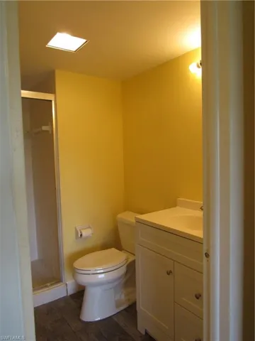 Bathroom with walk in shower, tile flooring, toilet, and vanity