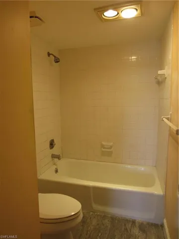 Bathroom featuring hardwood / wood-style flooring, toilet, and tiled shower / bath combo