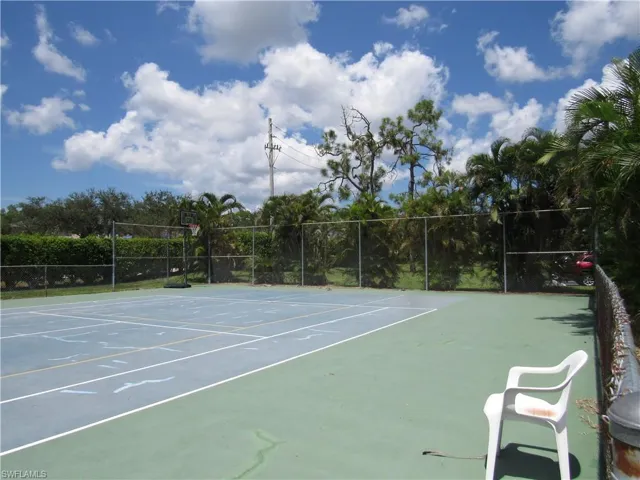 View of tennis court featuring basketball hoop