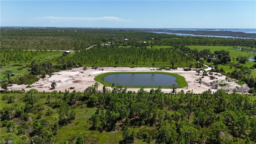 Aerial view of property and surrounding area featuring a large body of water and a heavily wooded area
