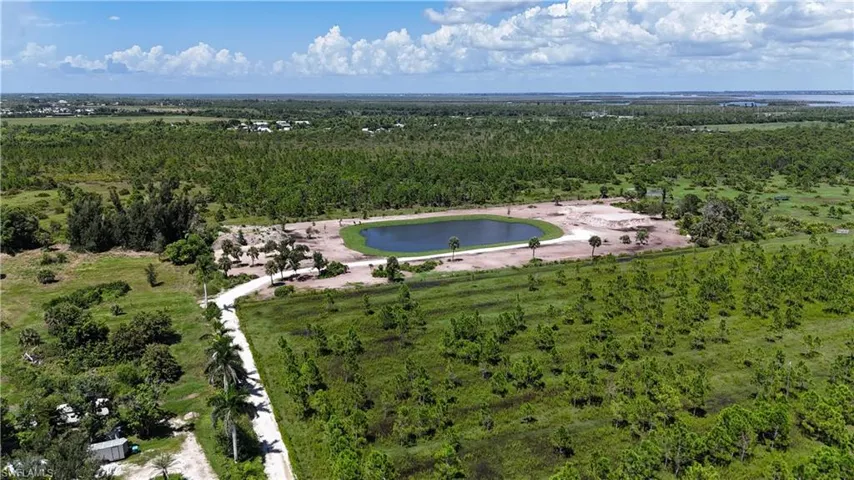 Aerial view of property's location with a heavily wooded area and a nearby body of water