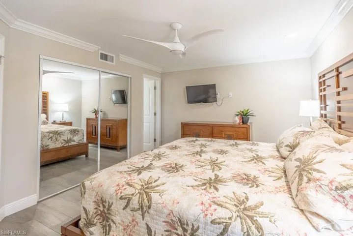 Bedroom featuring a closet, ornamental molding, wood finished floors, a ceiling fan, and baseboards