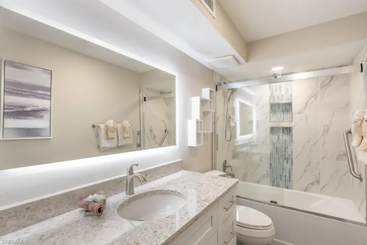 Full bath with vanity, shower / bath combination with glass door, and toilet