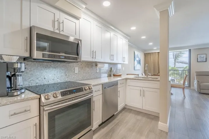 Kitchen featuring stainless steel appliances, a sink, tasteful backsplash, light wood-style floors, and white cabinets
