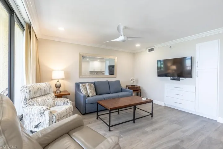 Living room featuring light wood finished floors, ceiling fan, ornamental molding, recessed lighting, and baseboards