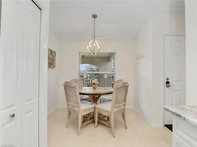 Dining space featuring light tile patterned floors, an inviting chandelier, and ornamental molding