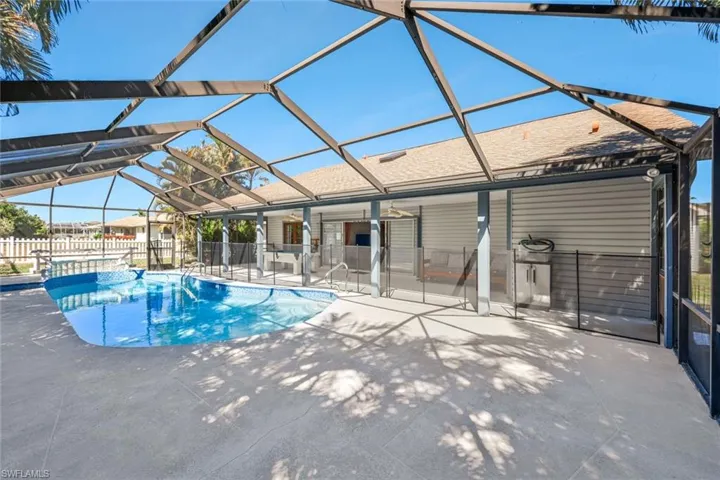 View of swimming pool featuring glass enclosure, a sunroom, and patio surround