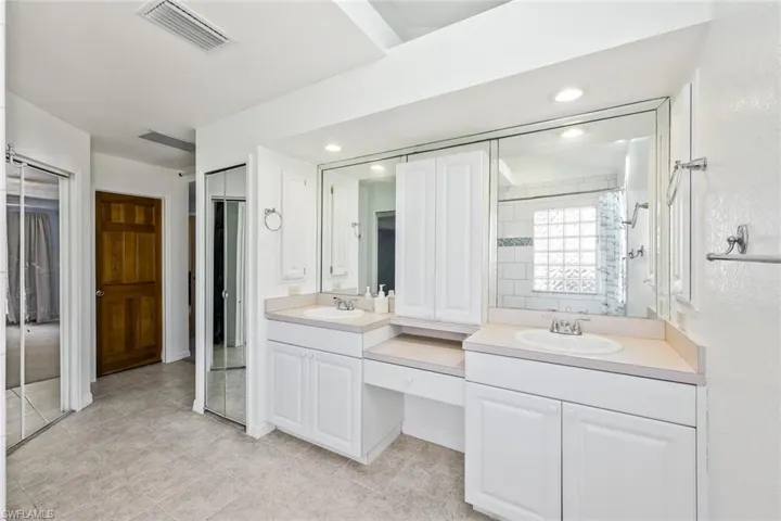 Full bath featuring two vanities, a closet, a shower, and recessed lighting