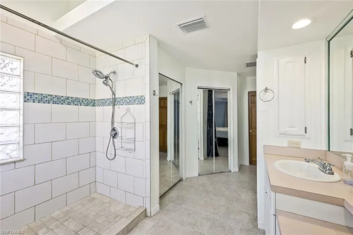 Full bath with vanity, tiled shower, a closet, and connected bathroom