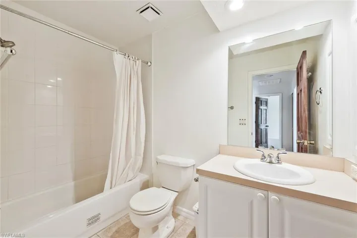 Bathroom featuring vanity and shower / bathtub combination with curtain