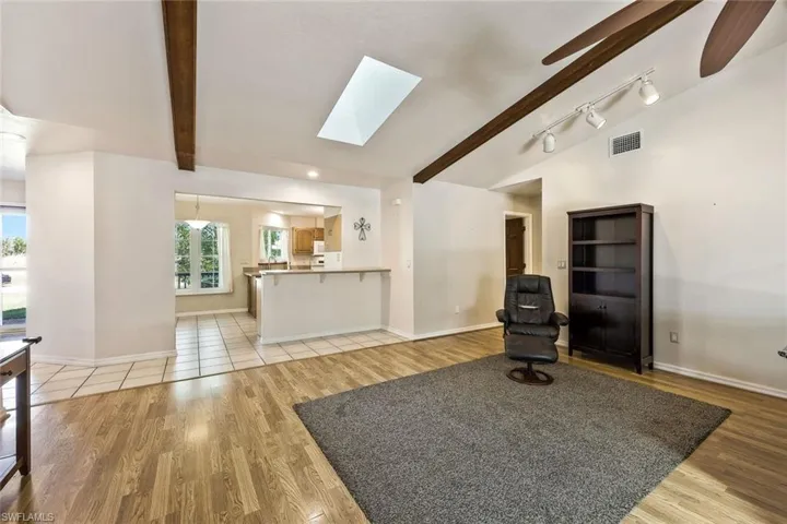 Sitting room featuring a skylight, lofted ceiling with beams, light wood finished floors, recessed lighting, and ceiling fan
