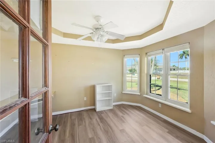 Spare room featuring a tray ceiling, light wood finished floors, and a ceiling fan