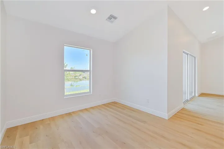 Unfurnished room featuring vaulted ceiling, light wood-type flooring, baseboards, and recessed lighting