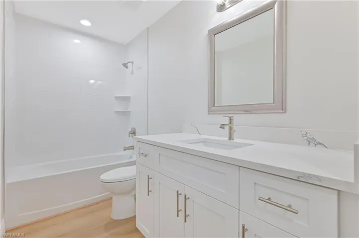 Full bath featuring wood finished floors, toilet, vanity, and  shower combination